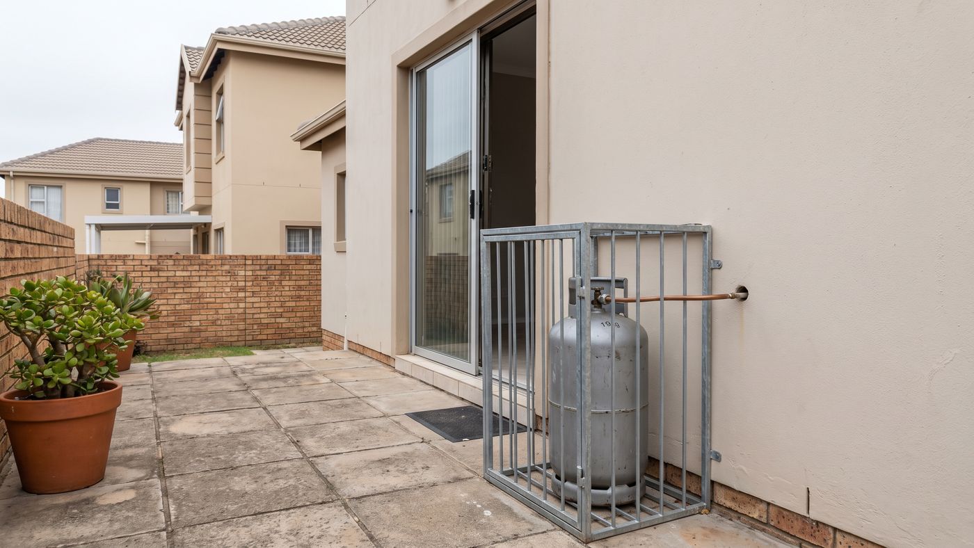 Caged gas cylinder on the patio of a townhouse in a security complex